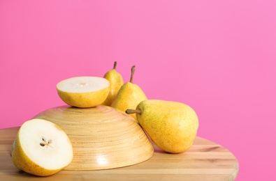 Photo of Fresh ripe pears on wooden table against color background. Space for text