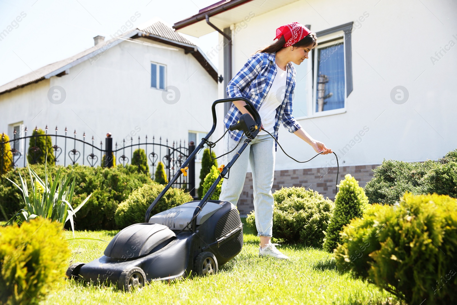 Photo of Woman cutting green grass with lawn mower in garden