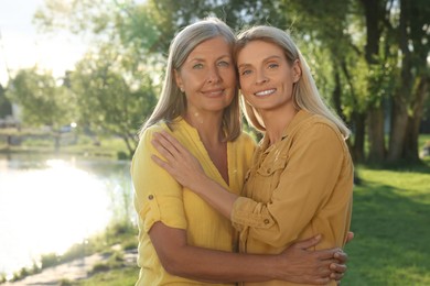 Photo of Family portrait of mother and daughter hugging in park on sunny day