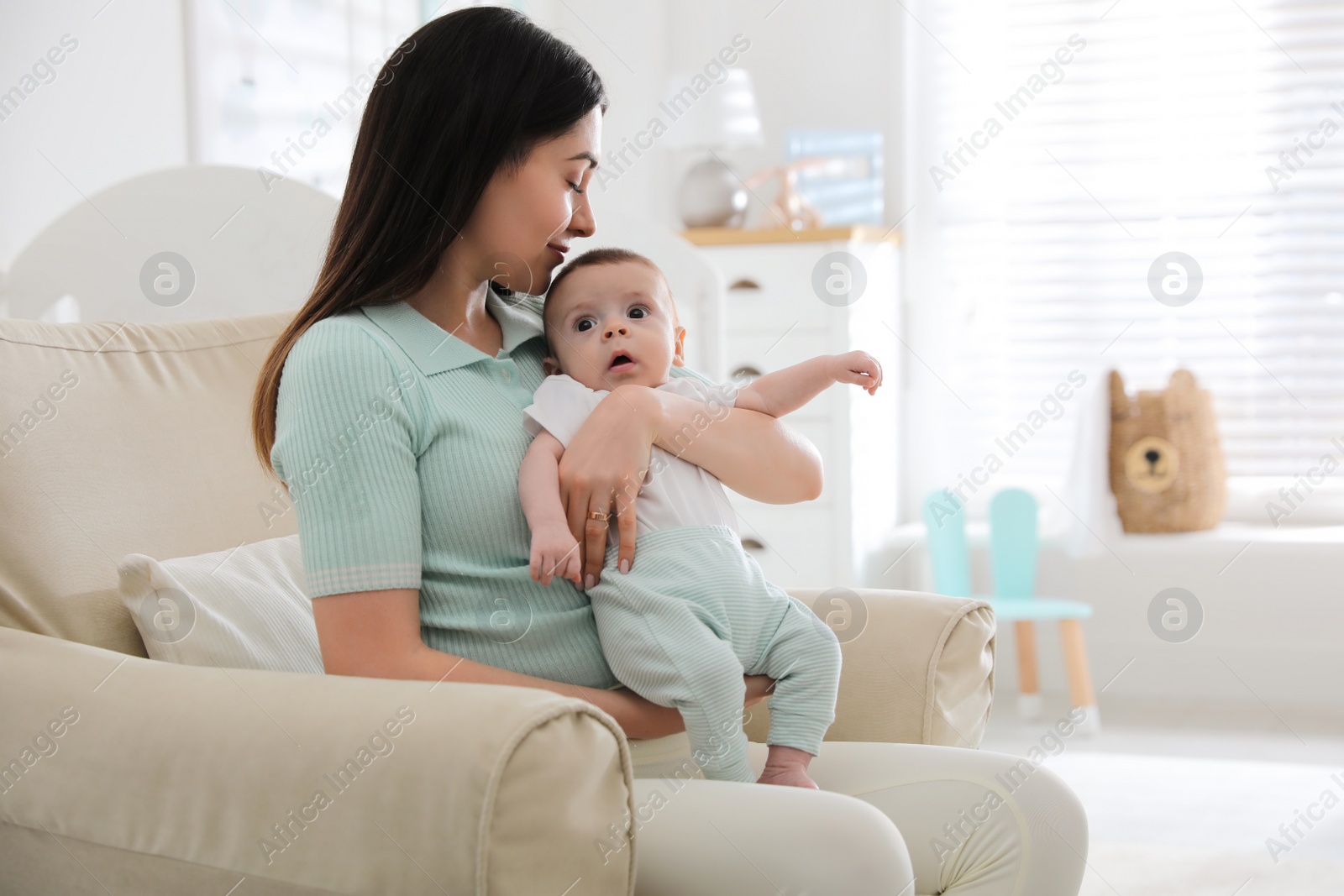 Photo of Young woman with her cute baby at home, space for text