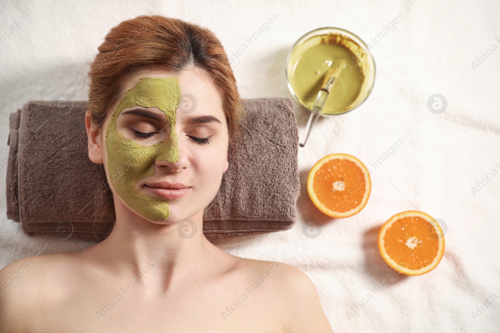 Photo of Beautiful woman with mask on face relaxing in spa salon, top view