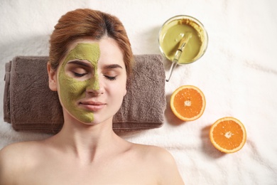 Beautiful woman with mask on face relaxing in spa salon, top view