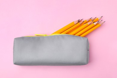 Photo of Many sharp pencils in pencil case on pink background, top view