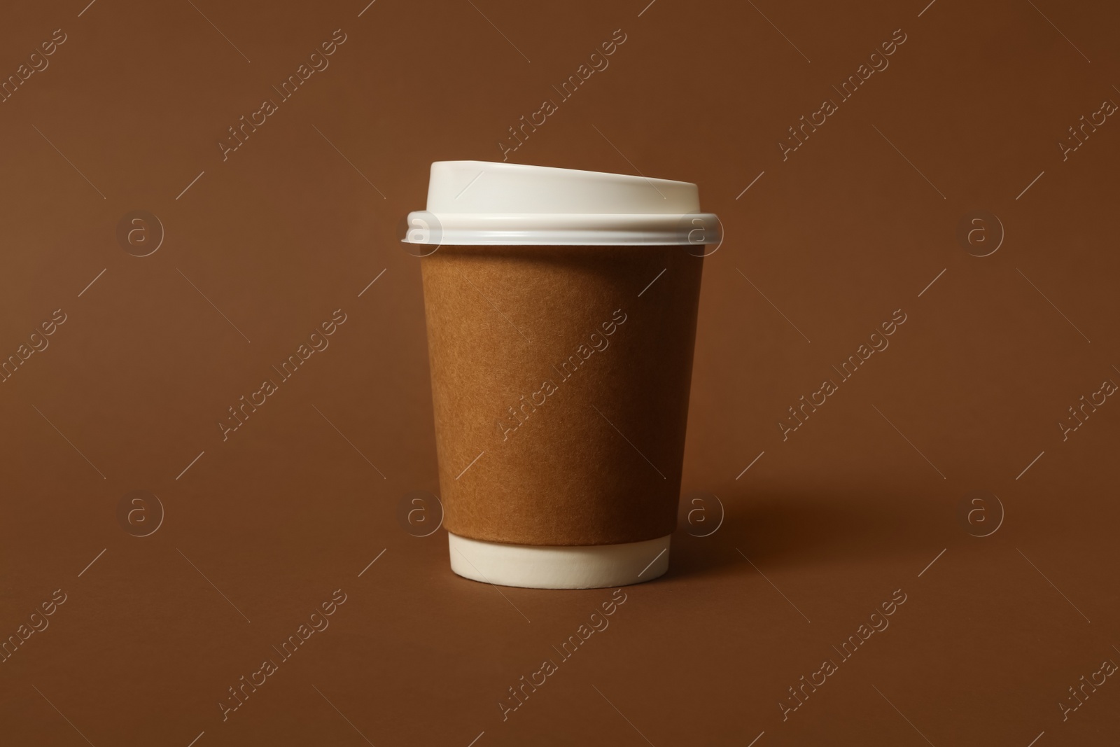 Photo of Takeaway paper coffee cup on brown background, closeup