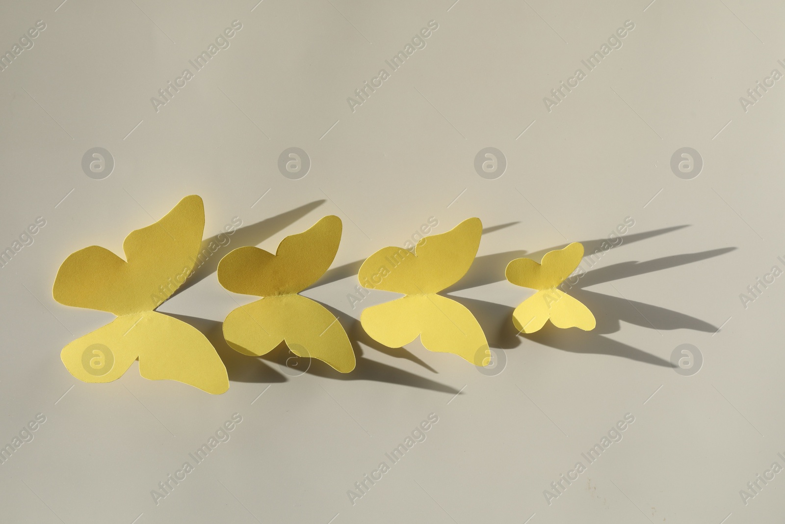 Photo of Yellow paper butterflies on light grey background, top view