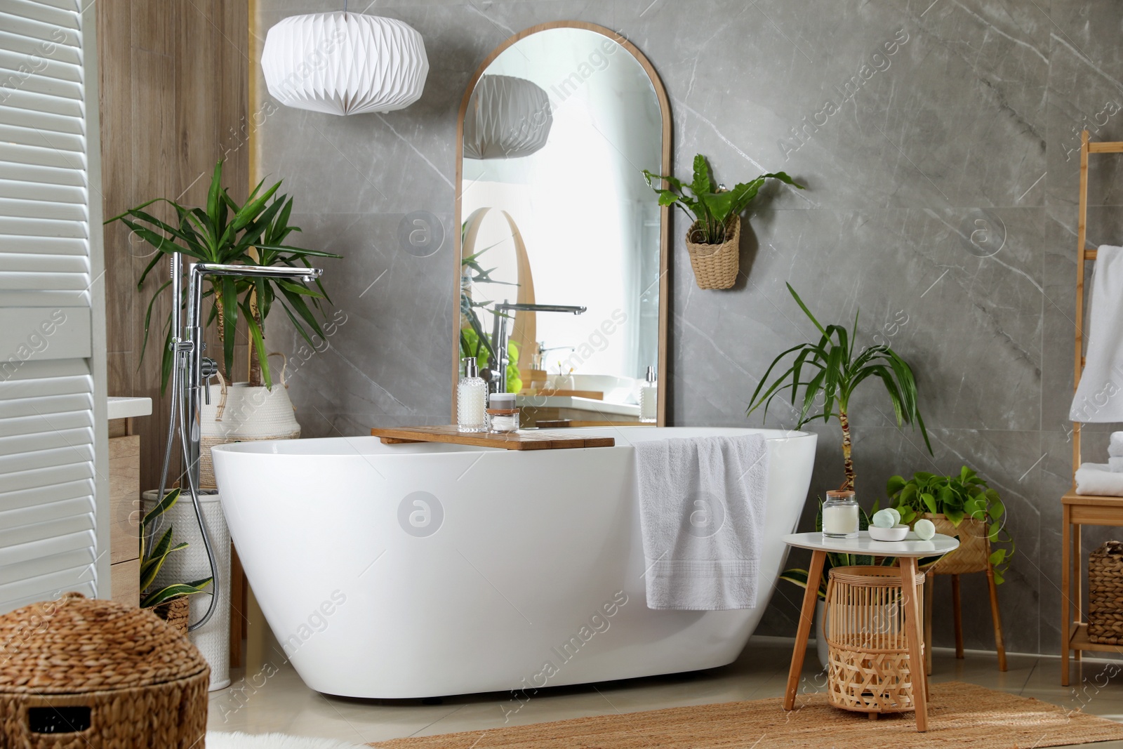 Photo of Modern white tub and beautiful green houseplants in bathroom. Interior design