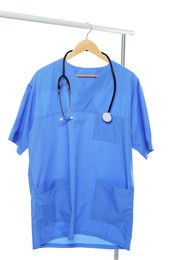 Light blue medical uniform and stethoscope on rack against white background