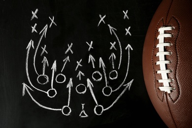Photo of Chalkboard with football game scheme and rugby ball, top view