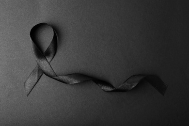 Photo of Black ribbon and space for text on dark background, top view. Funeral accessory