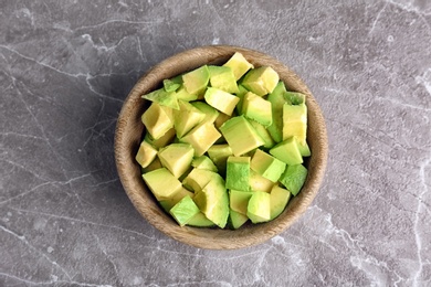 Photo of Bowl with cut avocado on grey background, top view