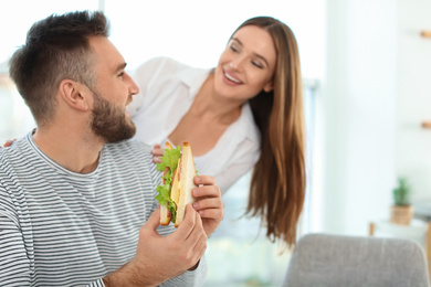 Happy couple having breakfast with sandwiches at home