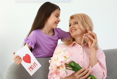Photo of Little daughter congratulating her mature mom at home. Happy Mother's Day