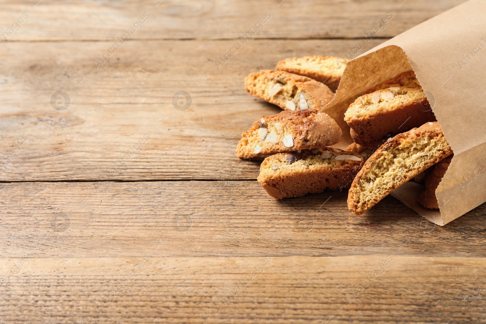 Photo of Traditional Italian almond biscuits (Cantucci) on wooden table, space for text