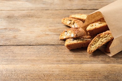 Photo of Traditional Italian almond biscuits (Cantucci) on wooden table, space for text