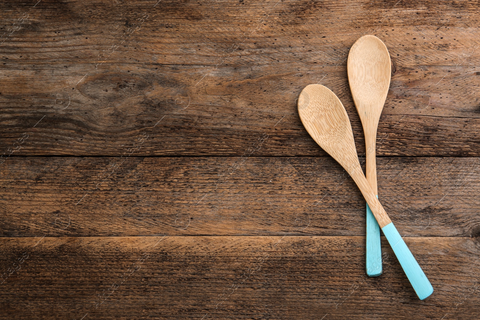 Photo of Clean empty bamboo spoons on wooden background, top view. Space for text