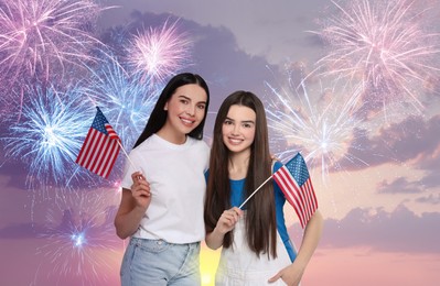 Image of 4th of July - Independence day of America. Happy mother and daughter holding national flags of United States against sky with fireworks