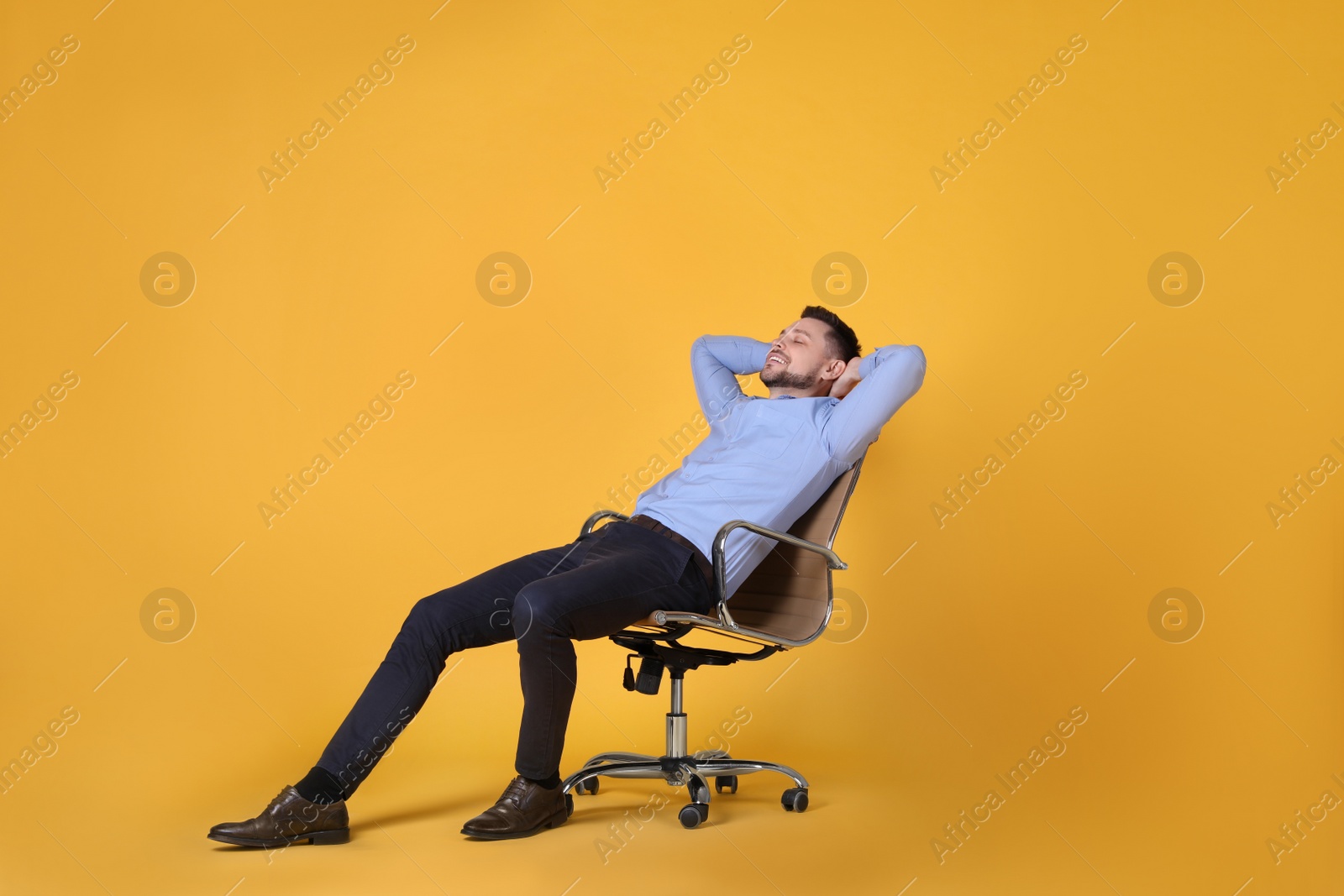 Photo of Handsome man relaxing in office chair on yellow background