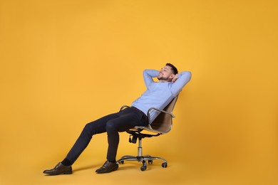 Photo of Handsome man relaxing in office chair on yellow background