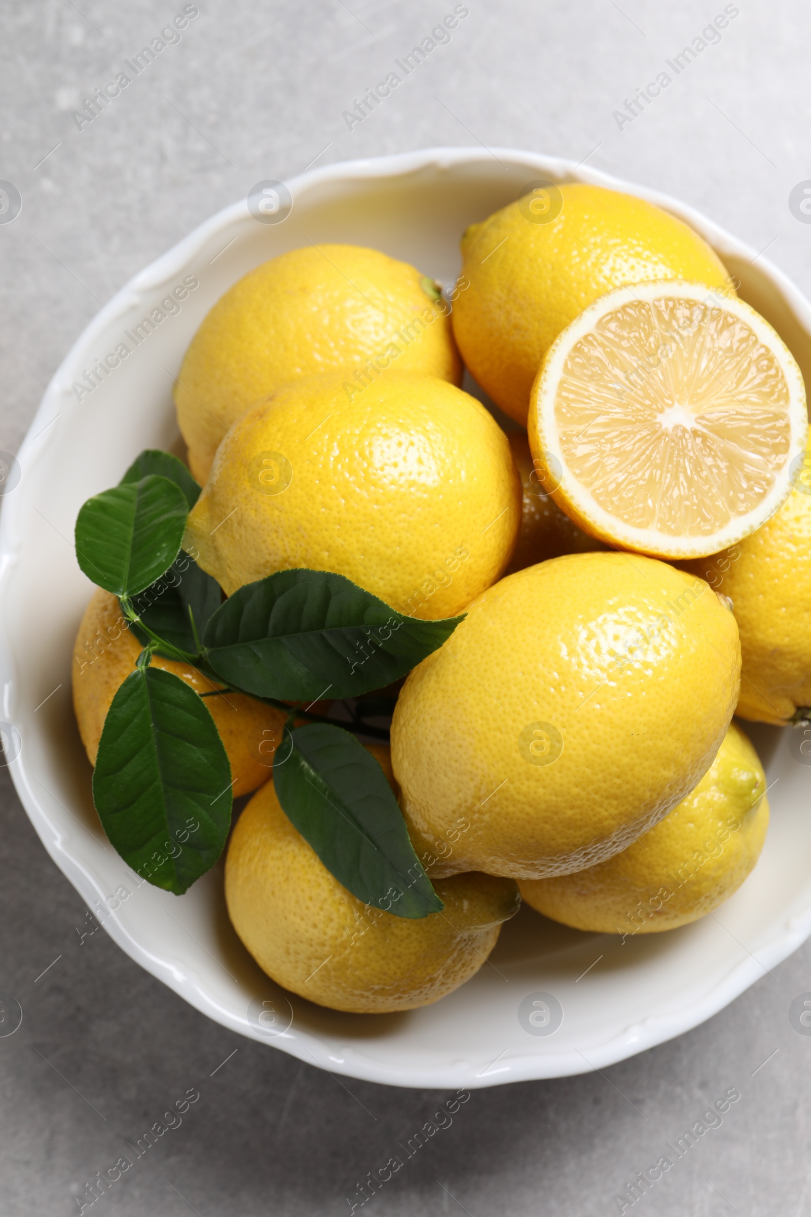 Photo of Fresh lemons and green leaves on grey table, top view