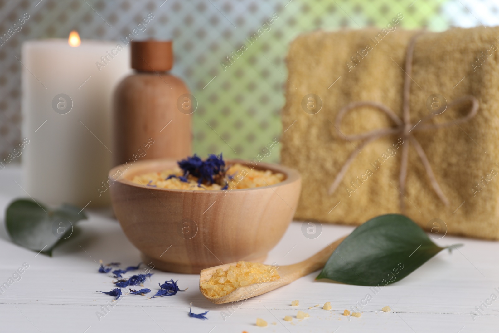 Photo of Spa composition. Sea salt, bottle of cosmetic product, towel and burning candle on white table