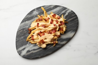 Photo of Delicious French fries with bacon and cheese sauce on white marble table, top view