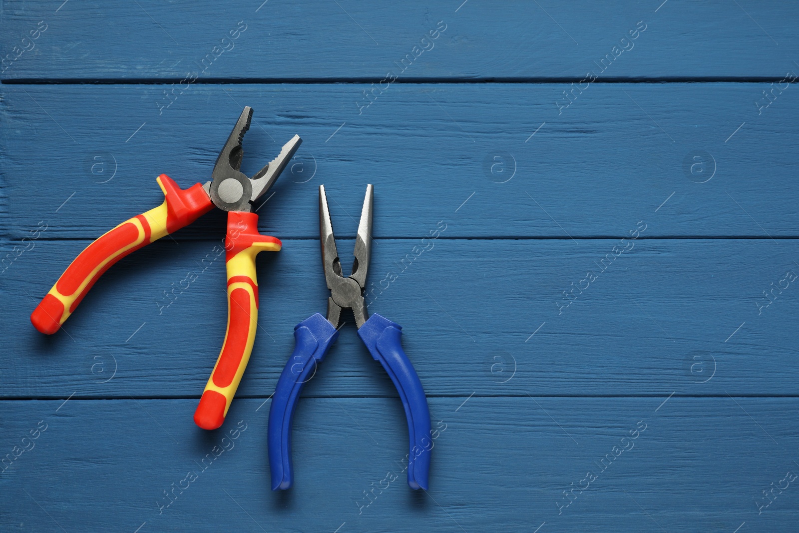 Photo of Pliers on blue wooden table, flat lay. Space for text