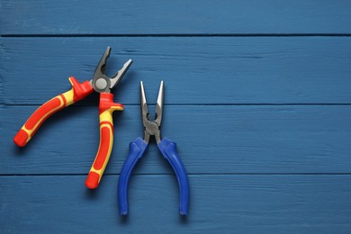 Photo of Pliers on blue wooden table, flat lay. Space for text