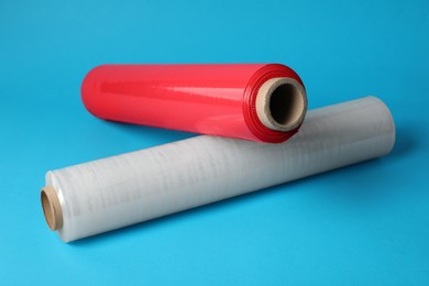 Photo of Rolls of different plastic stretch wrap on light blue background