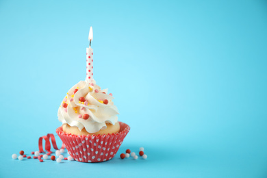 Photo of Delicious birthday cupcake with candle on light blue background. Space for text