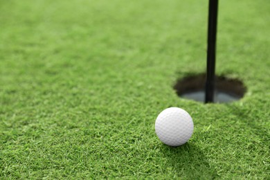 Photo of Golf ball near hole on green course, space for text