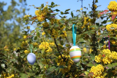 Photo of Beautifully painted Easter eggs hanging on tree outdoors