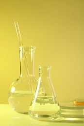 Photo of Laboratory analysis. Different glassware on table against yellow background