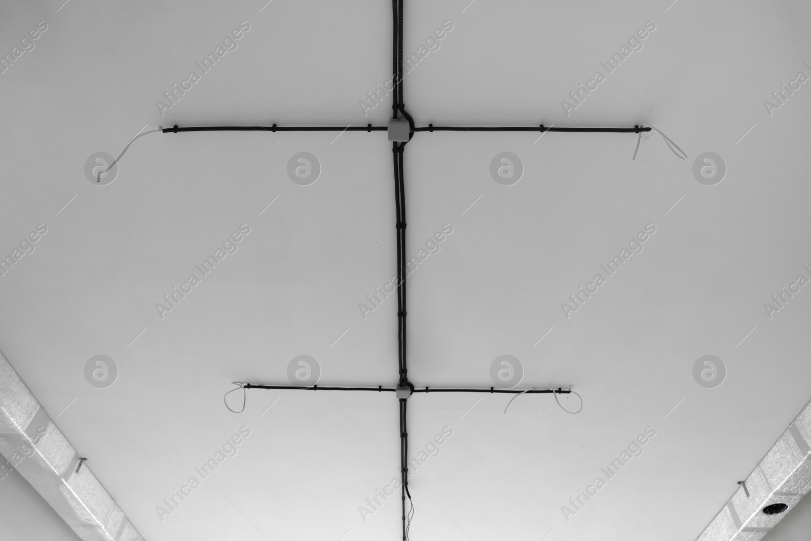 Photo of Black cables on white ceiling. Wiring system