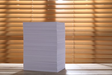 Photo of Stack of paper sheets on wooden table. Space for text