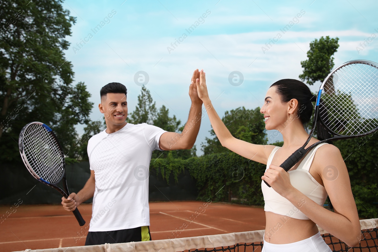 Photo of Woman giving man high five at tennis court