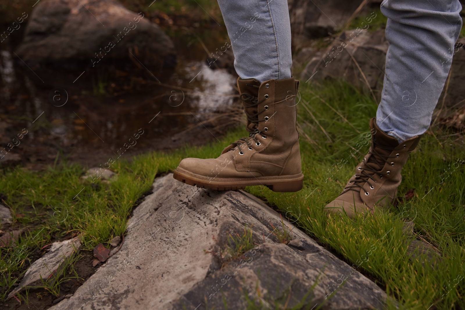 Photo of Woman wearing stylish hiking boots on rock, closeup