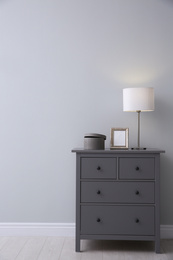 Photo of Modern grey chest of drawers near light wall in room. Interior design