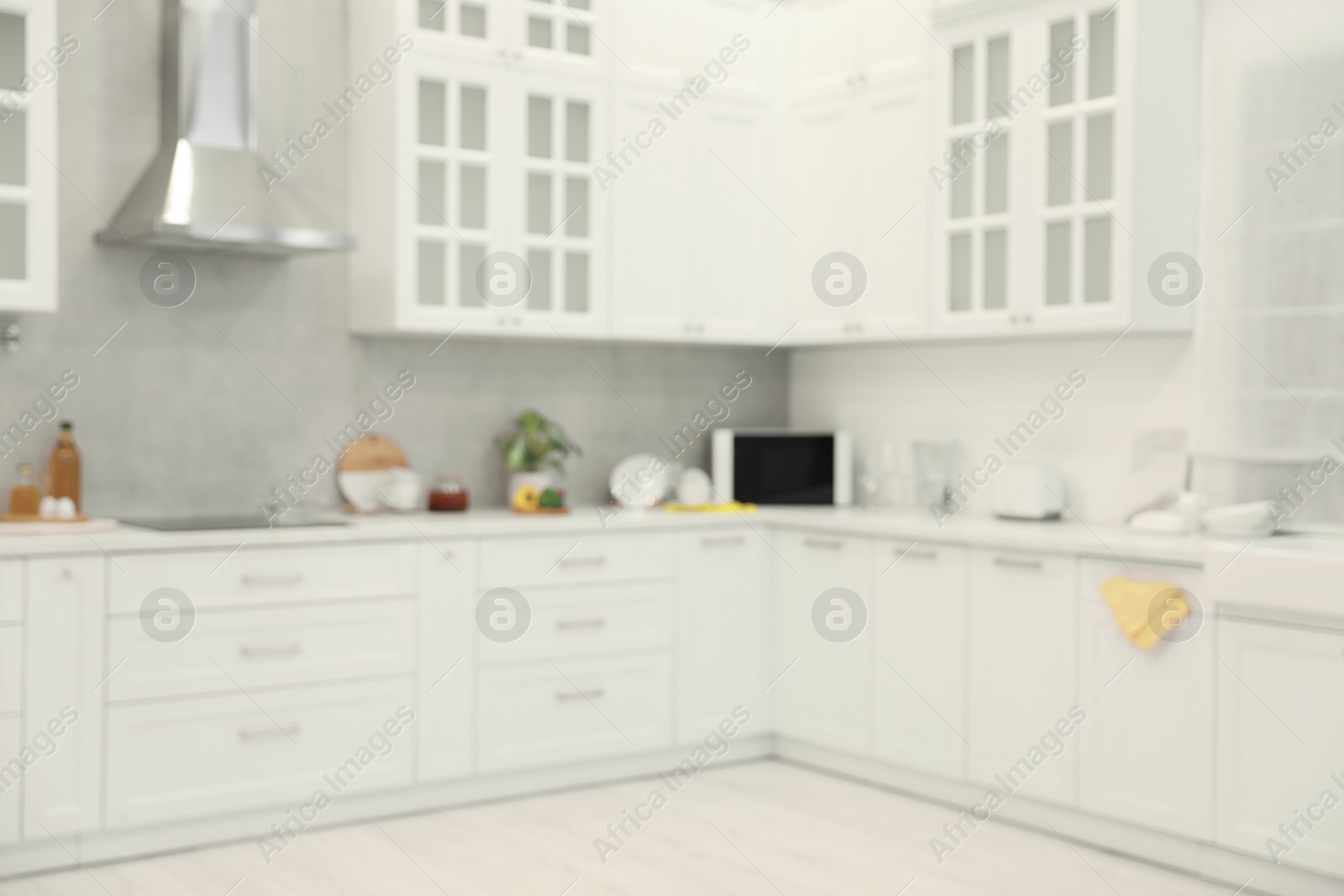 Photo of White cosy kitchen with furniture, blurred view. Interior design