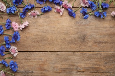 Photo of Beautiful colorful cornflowers on wooden background, flat lay. Space for text