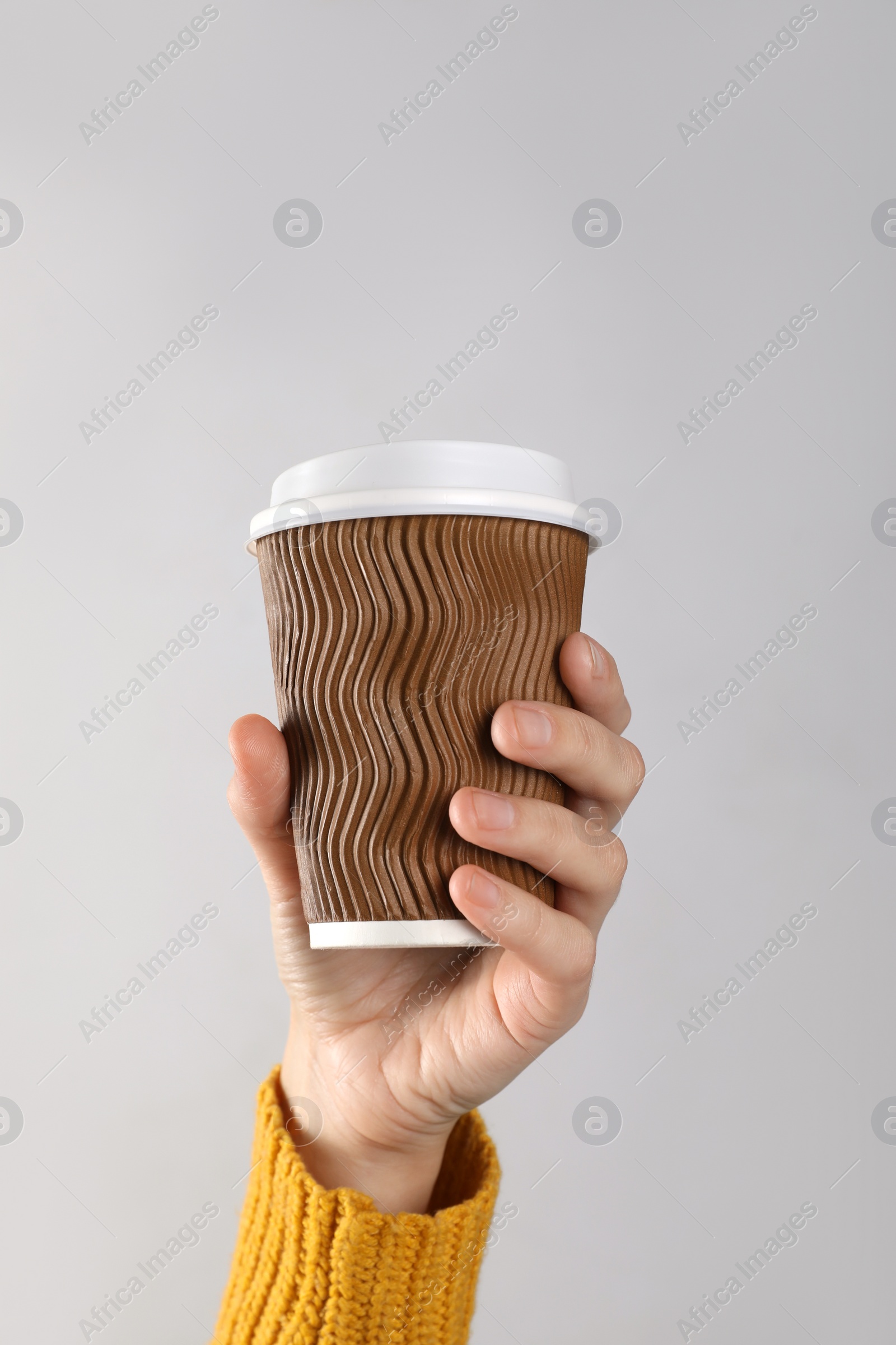 Photo of Woman holding takeaway paper coffee cup on white background, closeup