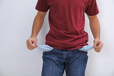 Photo of Man showing empty pockets on light background, closeup