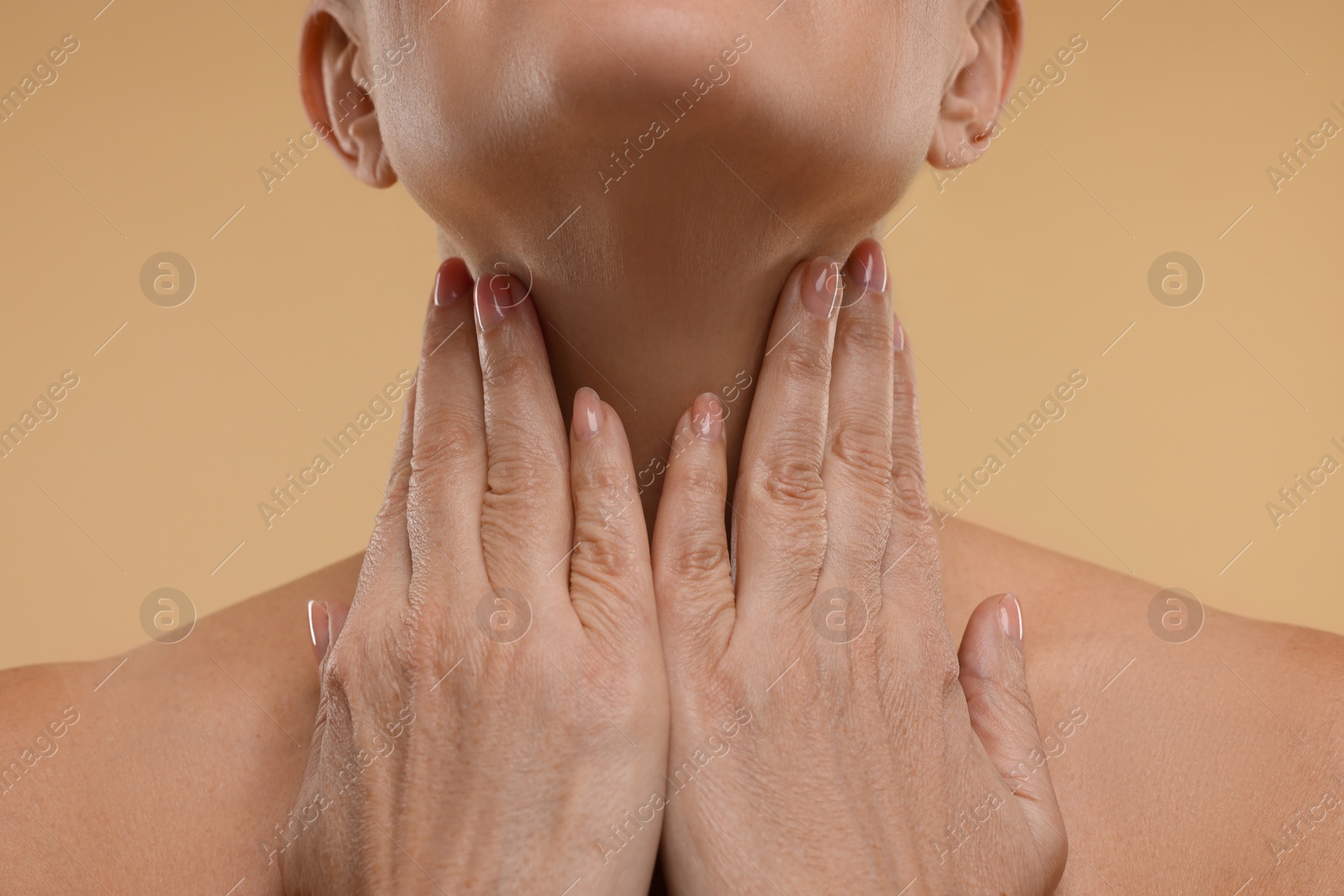 Photo of Mature woman touching her neck on beige background, closeup