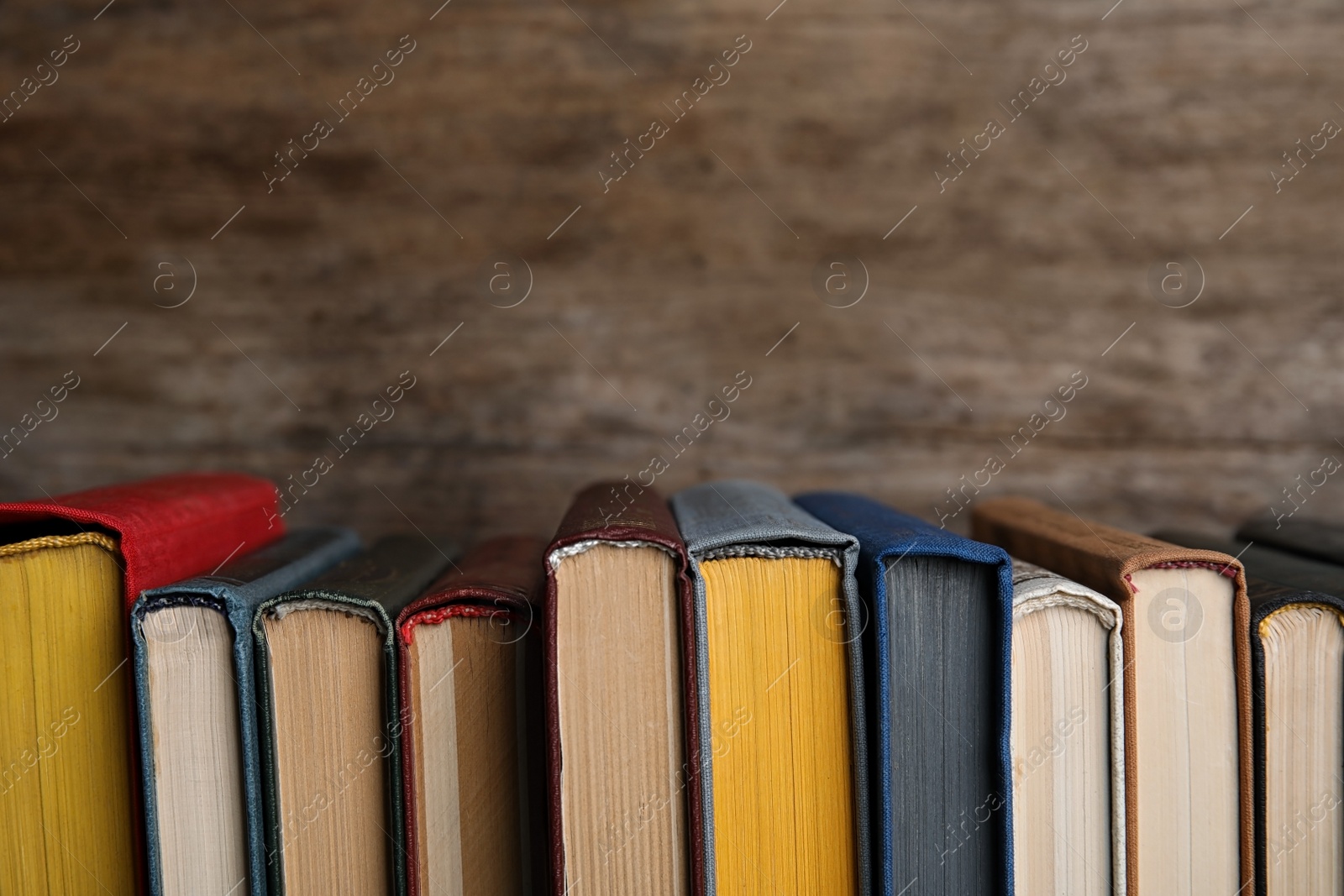 Photo of Stack of hardcover books on wooden background. Space for text