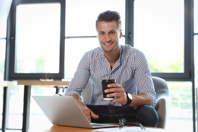 Photo of Male business trainer working with laptop in office