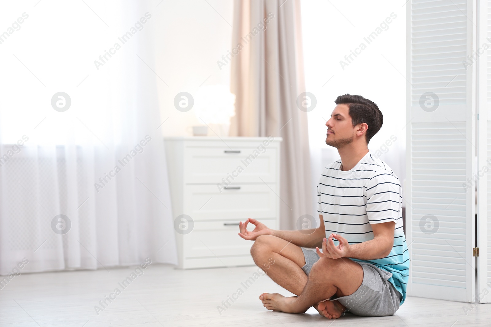 Photo of Man meditating on floor at home, space for text. Zen concept