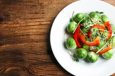 Photo of Tasty salad with Brussels sprouts on wooden table, top view. Space for text