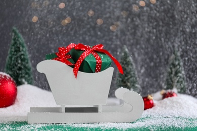 Photo of Sleigh with gift boxes on turquoise wooden table during snowfall