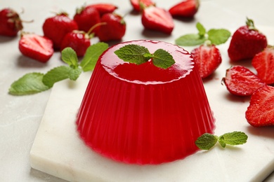 Stone board with fruit jelly, strawberries and mint on light table