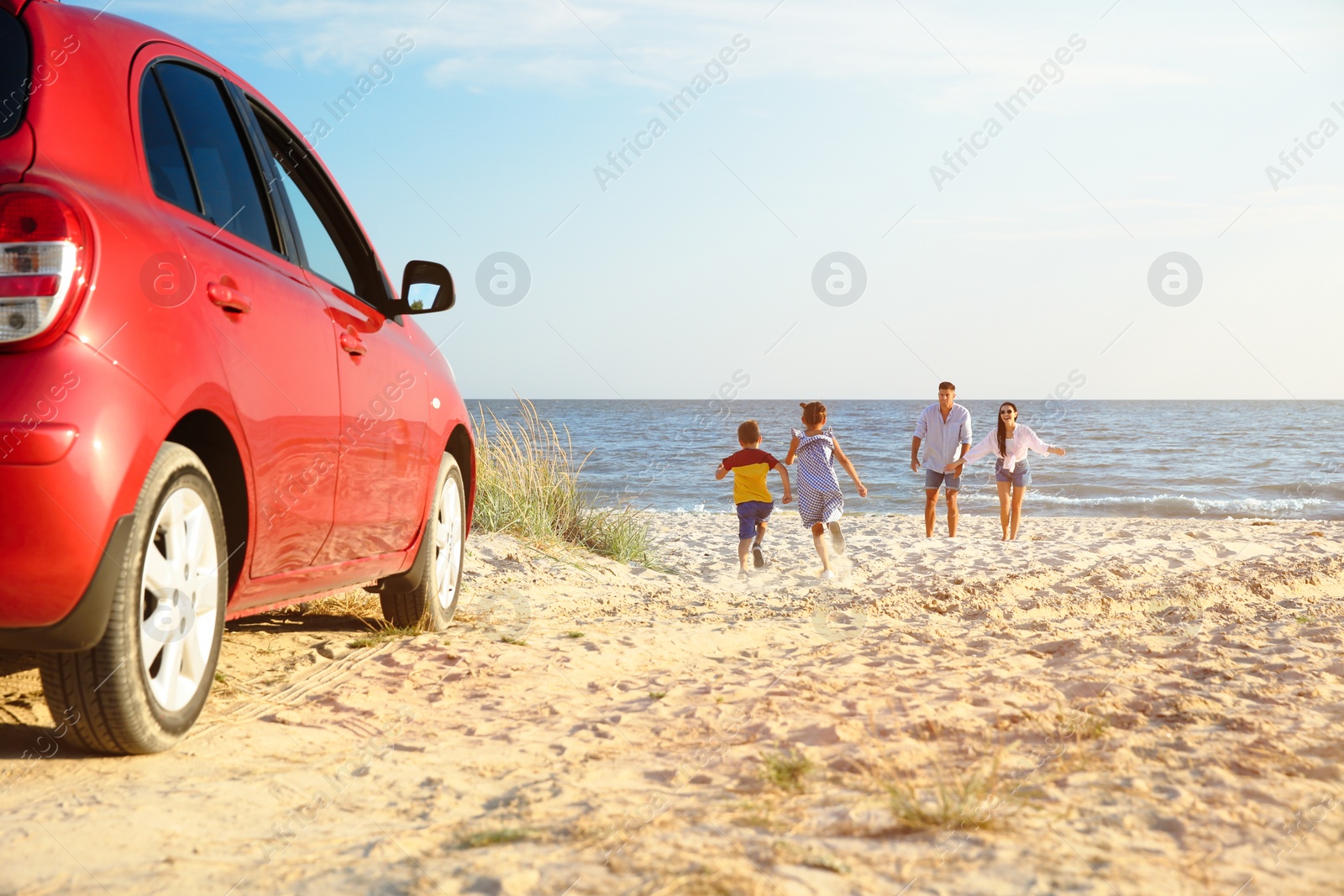 Photo of Little children running to their parents on sandy beach. Summer trip