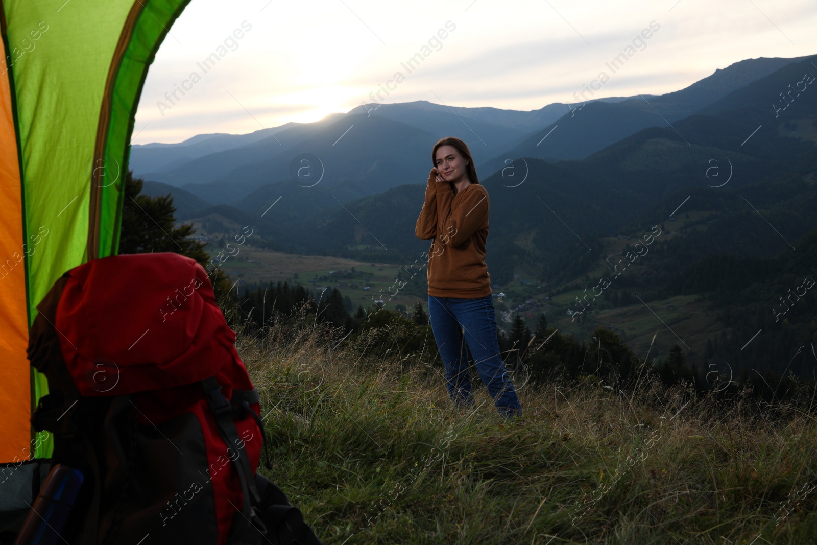 Photo of Young woman in mountains, view from camping tent